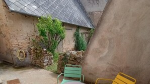 Een terras met een ronde tafel en vier stoelen in blauw, groen, geel en rood.