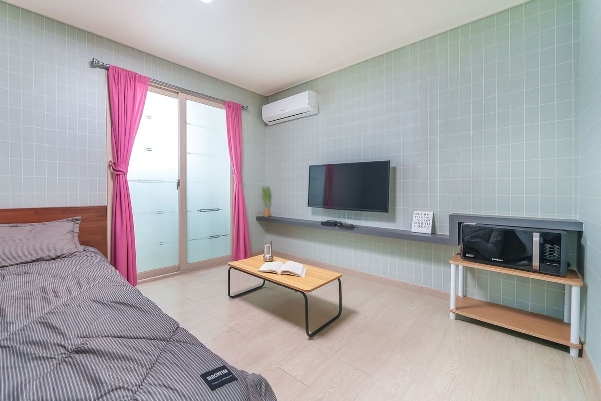 Een hotelkamer met een bed, een televisie, een klein tafeltje en een magnetron.