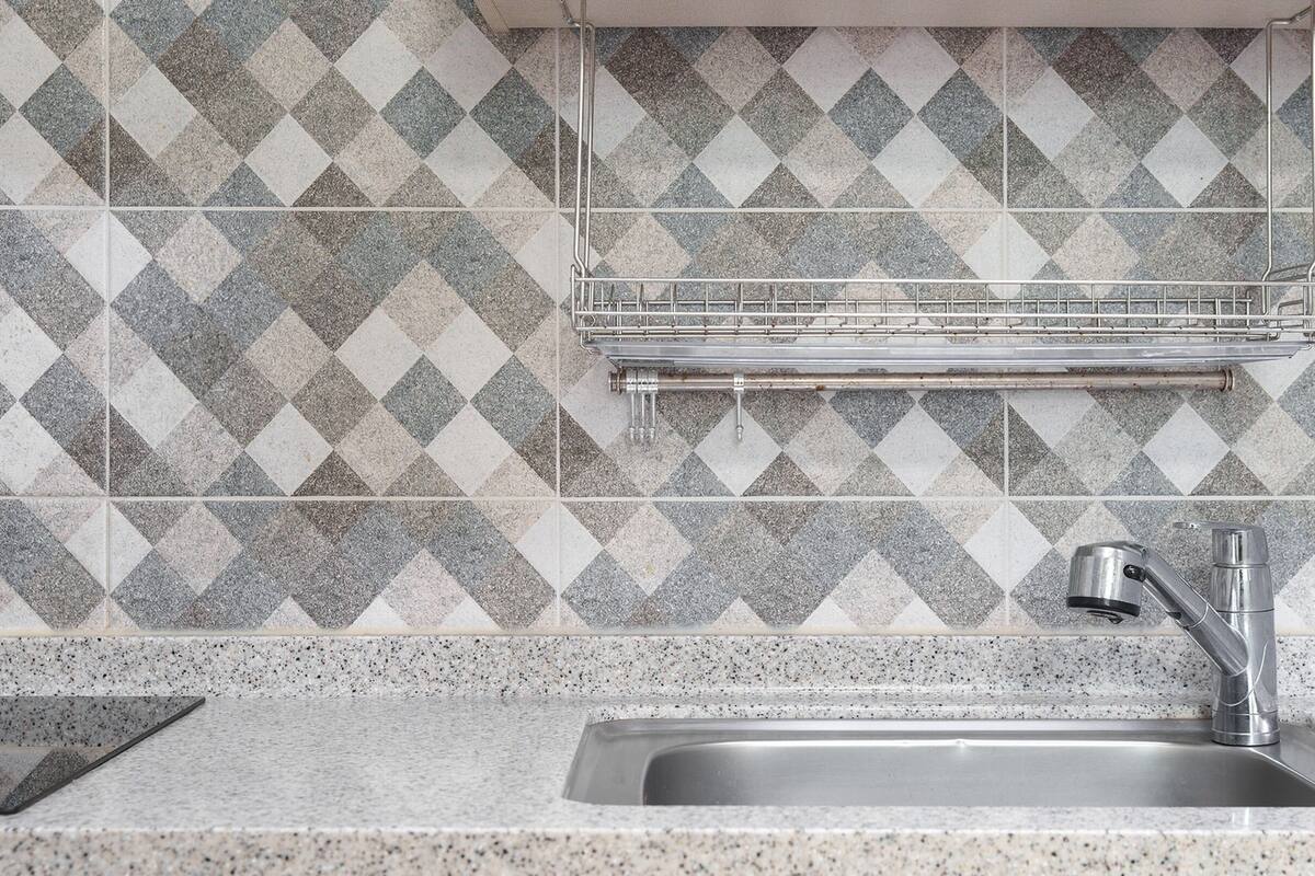 Een keuken met een granieten aanrecht, een roestvrijstalen spoelbak en een backsplash met een diamantpatroon.
