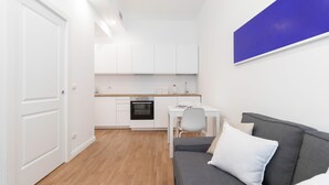 Un espacio habitable compacto con kitchenette, comedor y sofá.