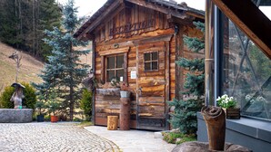 A rustic wooden cabin with a reception area, surrounded by trees and a cobblestone path. - Alpine Mountain Chalet (Marebbe)