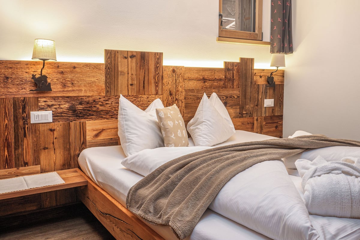 A wooden headboard bed with white linens and multiple pillows.
