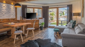 A cozy living room with a wooden dining table, a sofa, and a television. - Alpine Mountain Chalet (Marebbe)