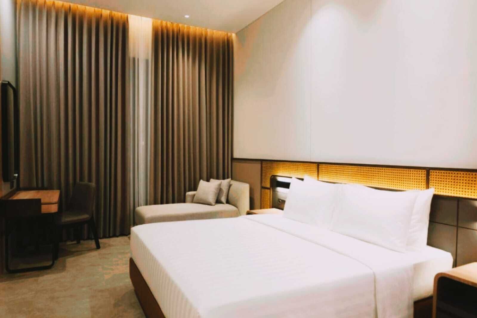 A hotel room with a large bed, two bedside tables, a desk, and a chair.
