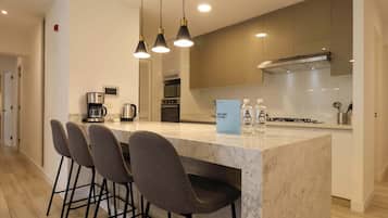 A modern kitchen with a marble island, bar stools, and pendant lighting.