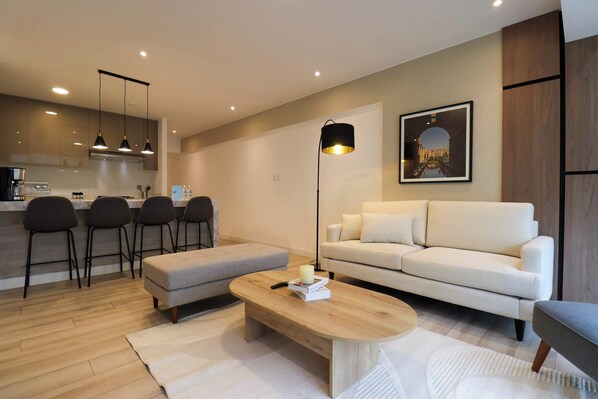 A modern living room with a sofa, a coffee table, and a dining area with chairs.