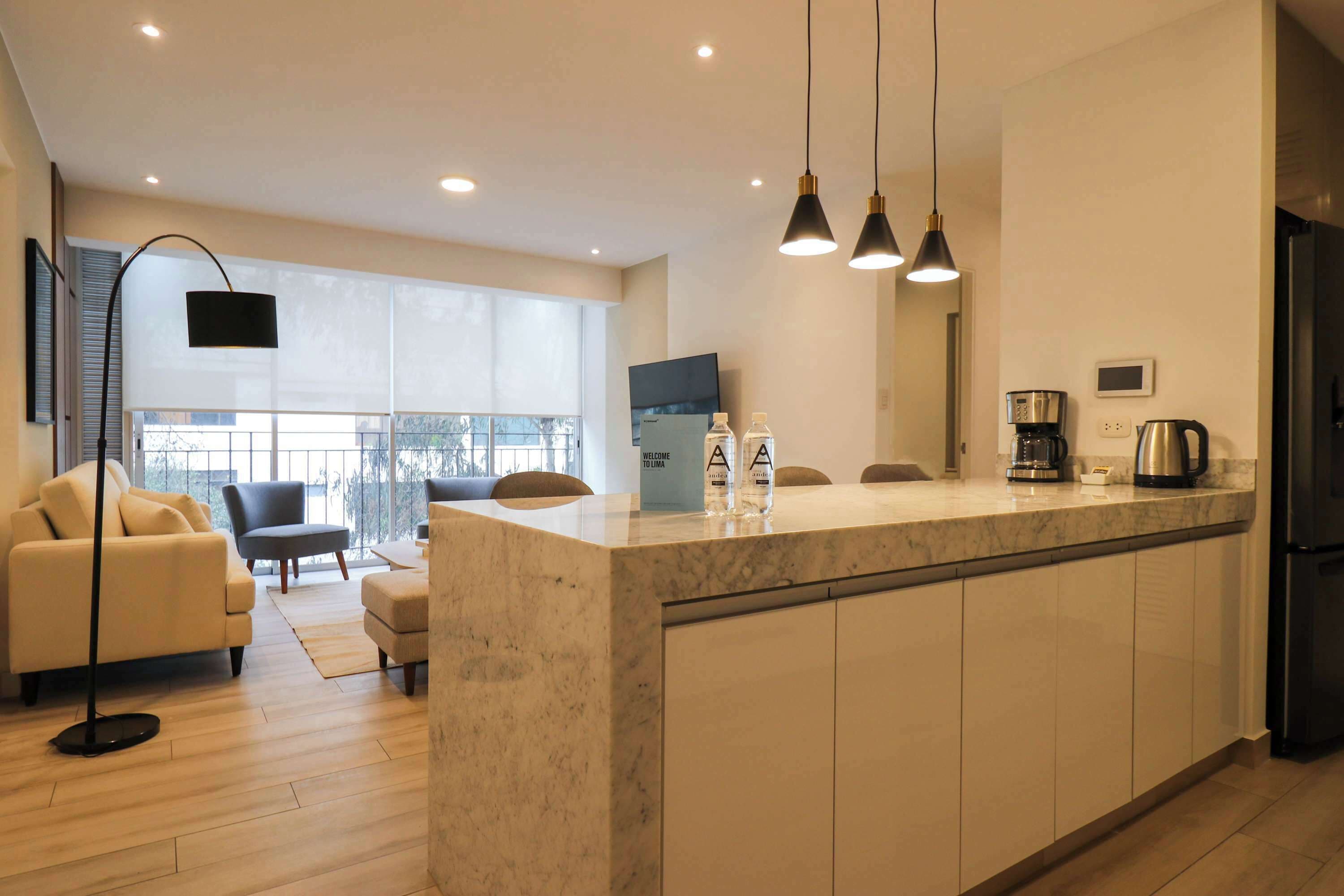 A modern kitchen with a marble countertop, a black refrigerator, and a coffee maker.