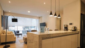 A modern kitchen with a marble countertop, a black refrigerator, and a coffee maker.