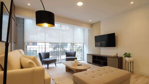 A modern living room with a sofa, armchairs, a coffee table, and a TV mounted on the wall.