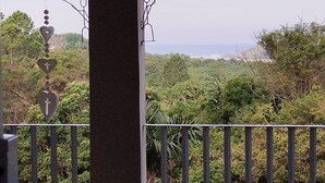 Ein Balkon mit Blick auf eine üppige Landschaft und den Ozean.