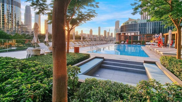 A rooftop pool with lounge chairs and a view of the city skyline. - Family 3BR Flat | Free Parking, Gym, Pool & Burj Views (Dubai)