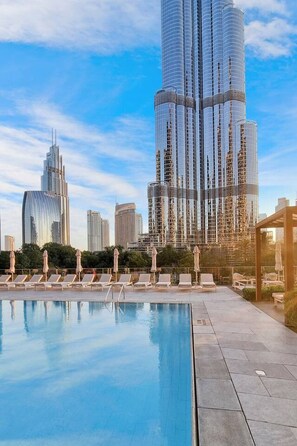 A modern hotel with a rooftop pool, surrounded by high-rise buildings. - Family 3BR Flat | Free Parking, Gym, Pool & Burj Views (Dubai)
