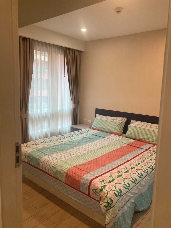 Un dormitorio con cama, cortinas y ventana.