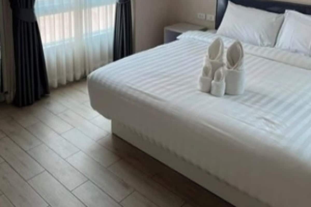 Une chambre d’hôtel avec un grand lit, une table de chevet et une fenêtre avec des rideaux.