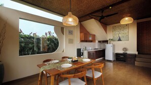 Une cuisine moderne avec des meubles en bois, un coin repas doté d’une grande fenêtre et un ventilateur de plafond.