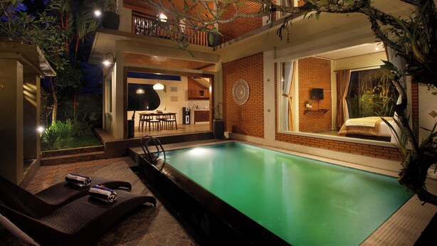 Une piscine extérieure avec des chaises longues et un espace repas.