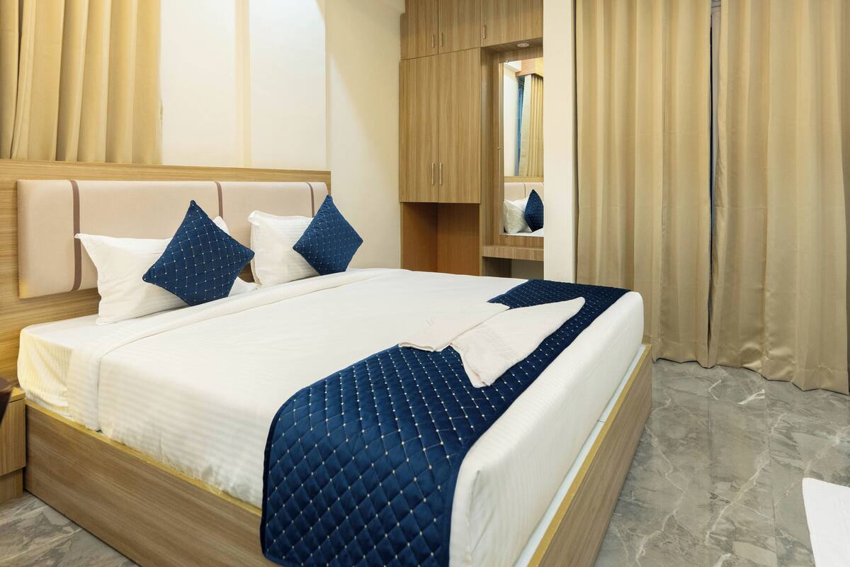 A modern hotel room with a large bed, wooden headboard, and a marble floor.