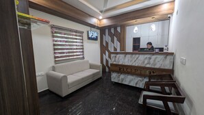 Een receptie met een marmeren balie, een bank en een aan de muur bevestigde televisie.