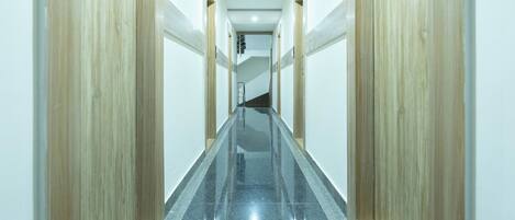 A long, narrow hallway with wooden doors on either side and a polished black floor.