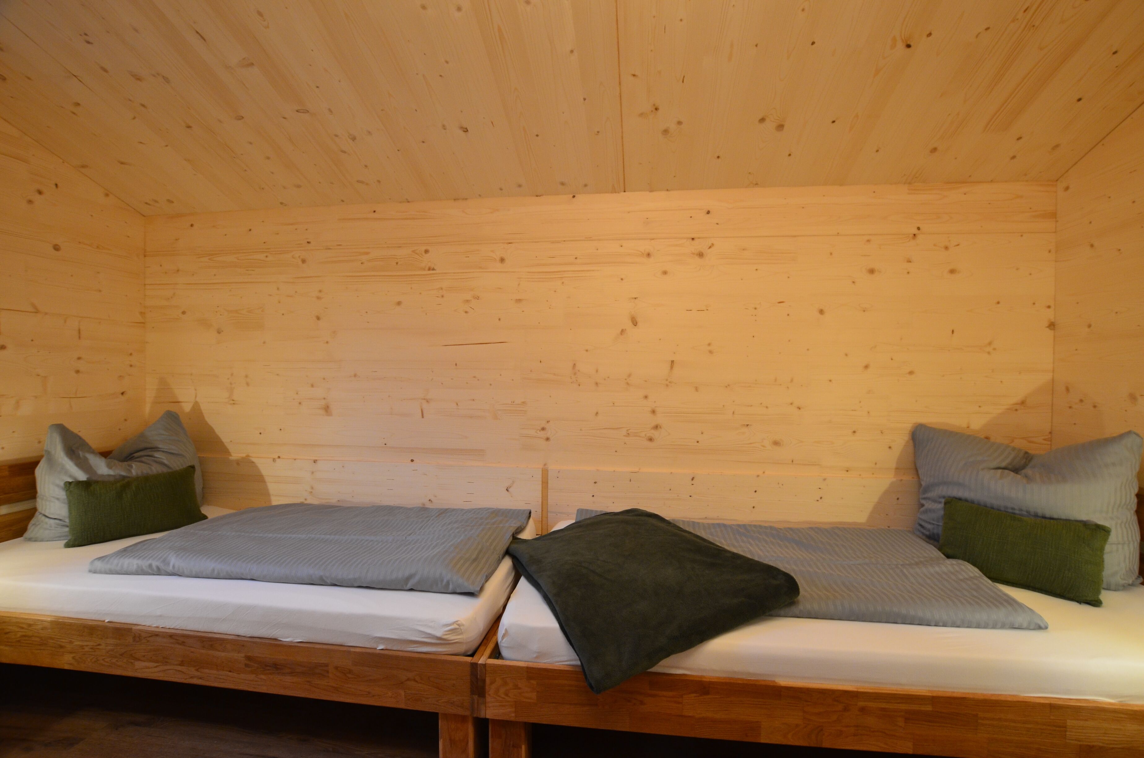 Una habitación de cabaña de madera con dos camas, cada una con almohadas y mantas.