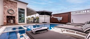 Ein Swimmingpool mit Liegestühlen und Grillplatz.