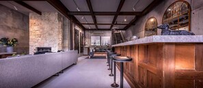 Eine Bar mit einer Steinwand, einer Holztheke und Barhocker.