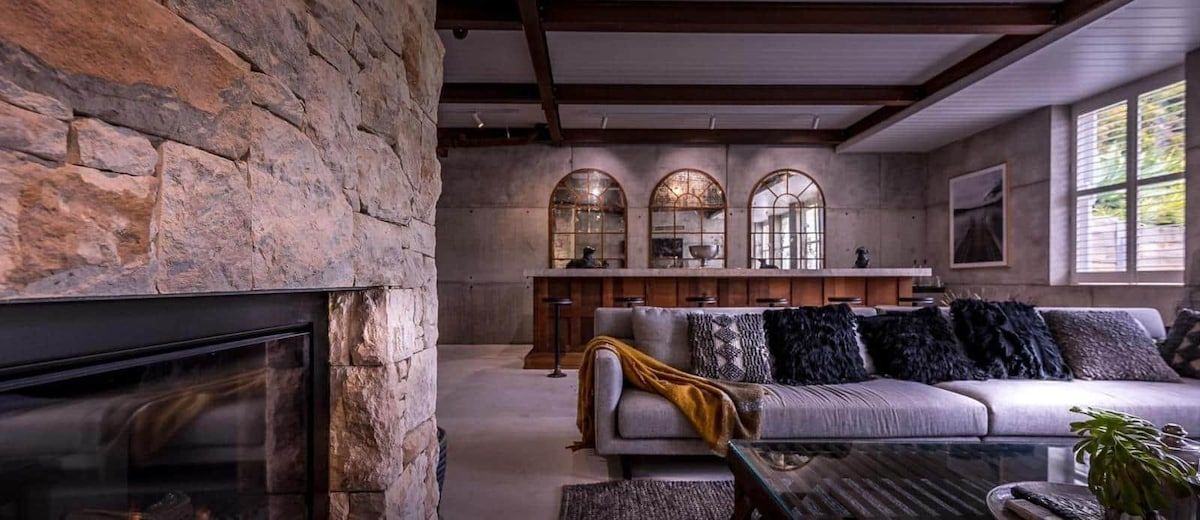 A living room with a stone wall, fireplace, sofa, and arched windows.