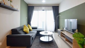 A modern living room with a sofa, coffee table, TV, and a plant.