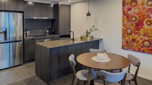 Eine moderne Küche mit Kochinsel, Edelstahlgeräten und einem Essbereich mit rundem Tisch und Stühlen.