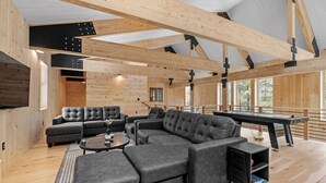 A spacious living area with a sectional sofa, a pool table, and wooden beams on the ceiling. - Ski Cabin w Hot Tub Gas Fireplace Near Cranmore (Conway)