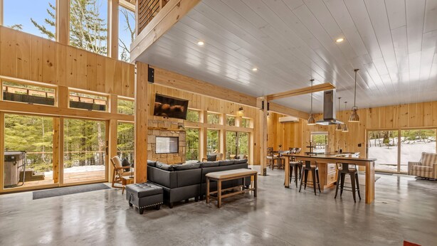 A spacious living area with a large sectional sofa, a dining table with bar stools, and a stone fireplace. - Ski Cabin w Hot Tub Gas Fireplace Near Cranmore (Conway)