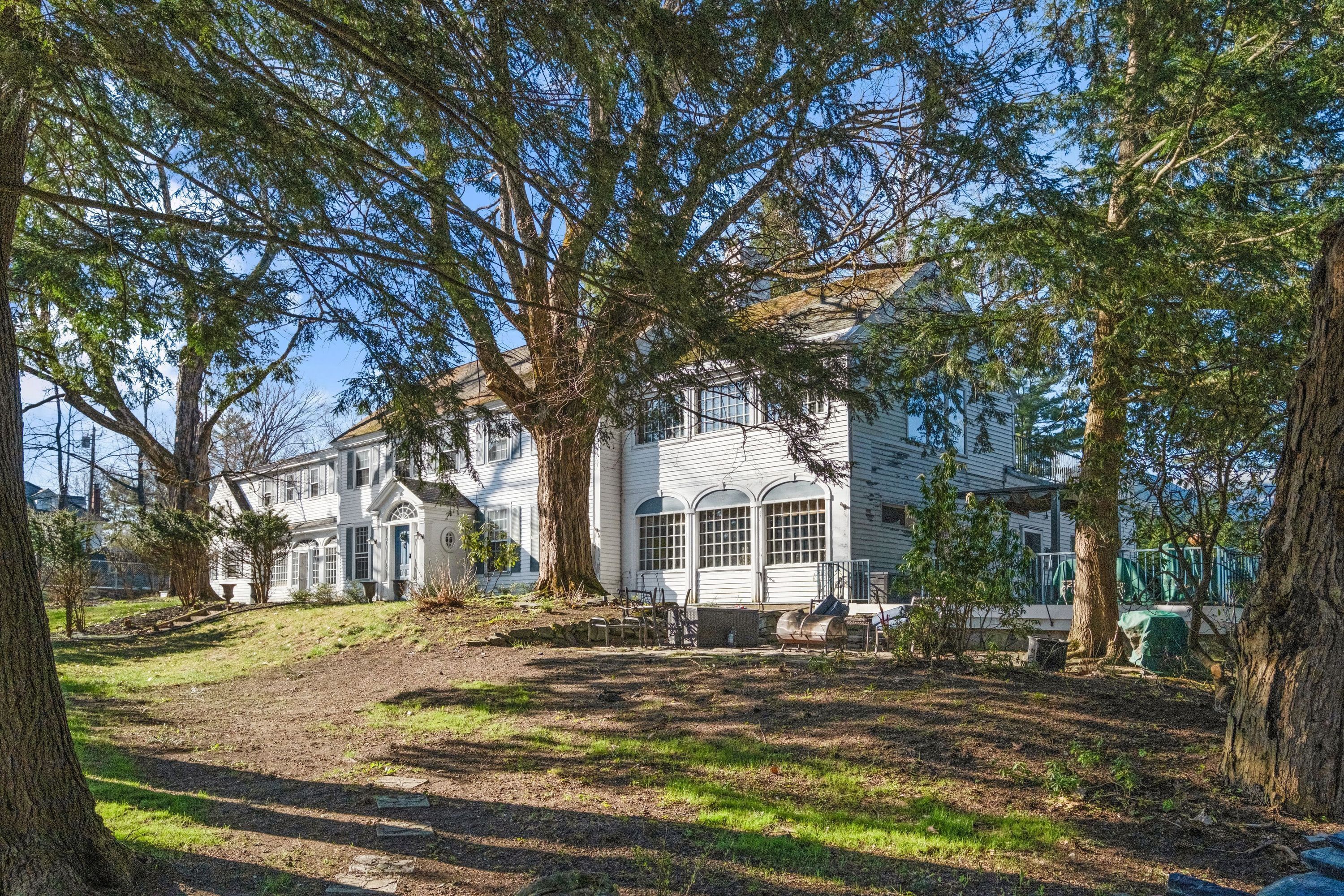 A large white house with a spacious yard, surrounded by trees.