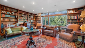 A spacious library with high ceilings, large windows, and a variety of bookshelves filled with books.