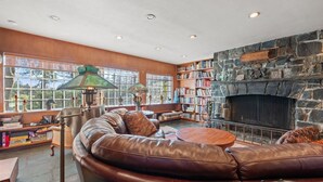 A cozy living room with a leather sofa, a fireplace, and a bookshelf.