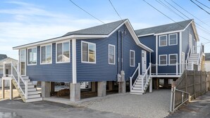 A two-story residential building with a gabled roof and a covered front porch. - Modern Condo Perfect For Winter Rental (Hampton)