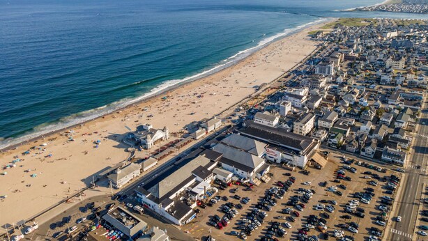 An aerial view of a coastal town with a beach, parking lots, and buildings. - Modern Condo Perfect For Winter Rental (Hampton)