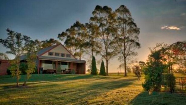 A house with a covered porch, surrounded by trees and a grassy yard.