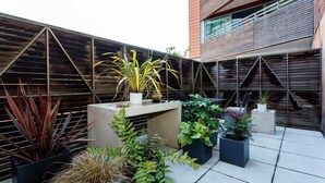 A rooftop garden with various potted plants and a concrete bench. - Zen By The Water, by Veeve (London)