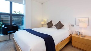 A modern hotel room with a large bed, bedside tables, a desk, and a chair. - Zen By The Water, by Veeve (London)