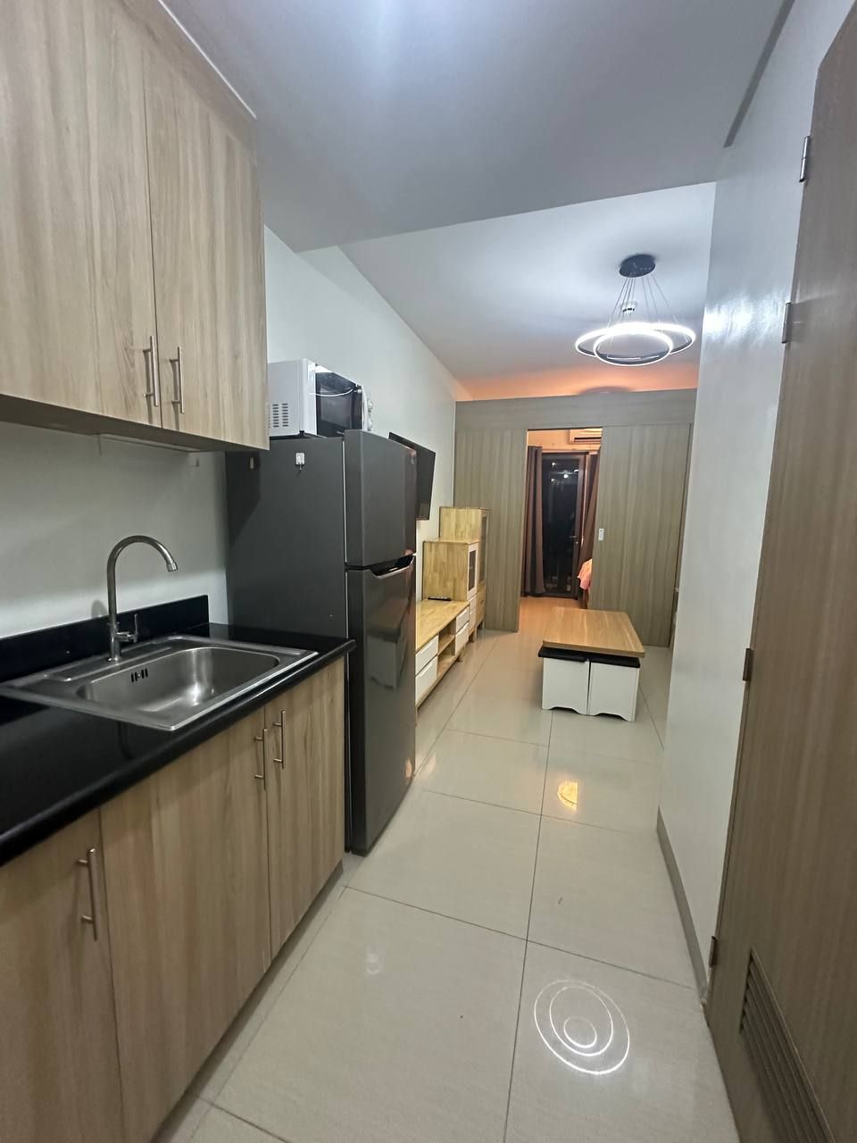 A modern kitchen with wooden cabinets, a stainless steel sink, and a built-in refrigerator.