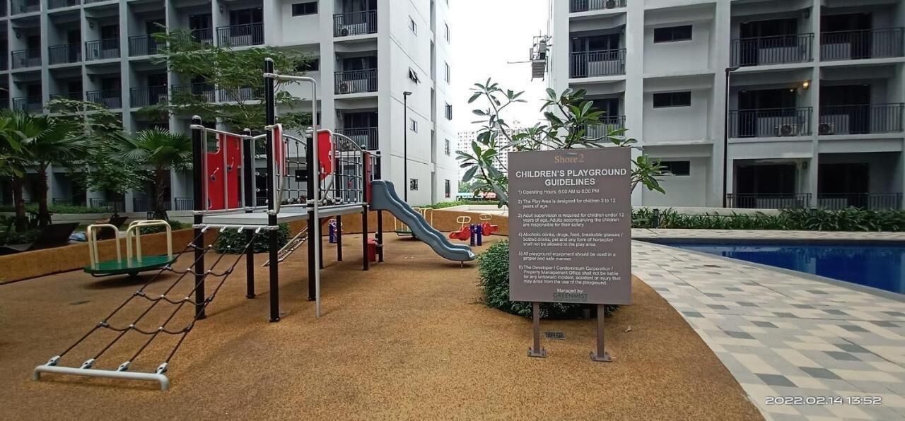 Un parque infantil con diversos juegos, incluyendo toboganes y estructuras para escalar, rodeado por un edificio con varios balcones.