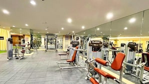 Une salle de sport équipée de divers appareils d’exercice, de miroirs et dotée d’un sol carrelé.