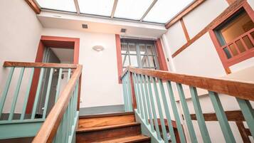 A staircase with wooden steps and teal railings leading to a room with a skylight.