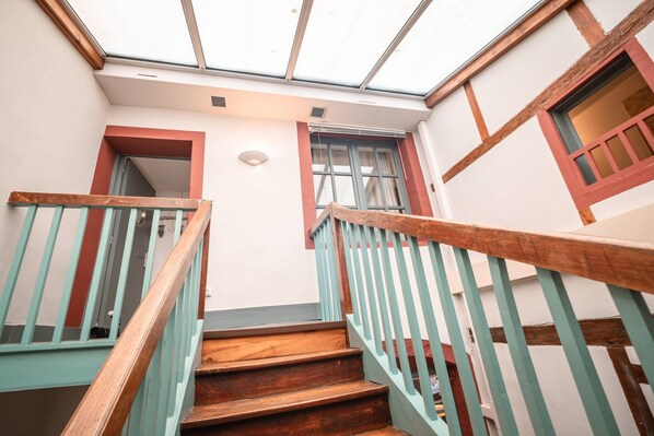 A staircase with wooden steps and teal railings leading to a room with a skylight.