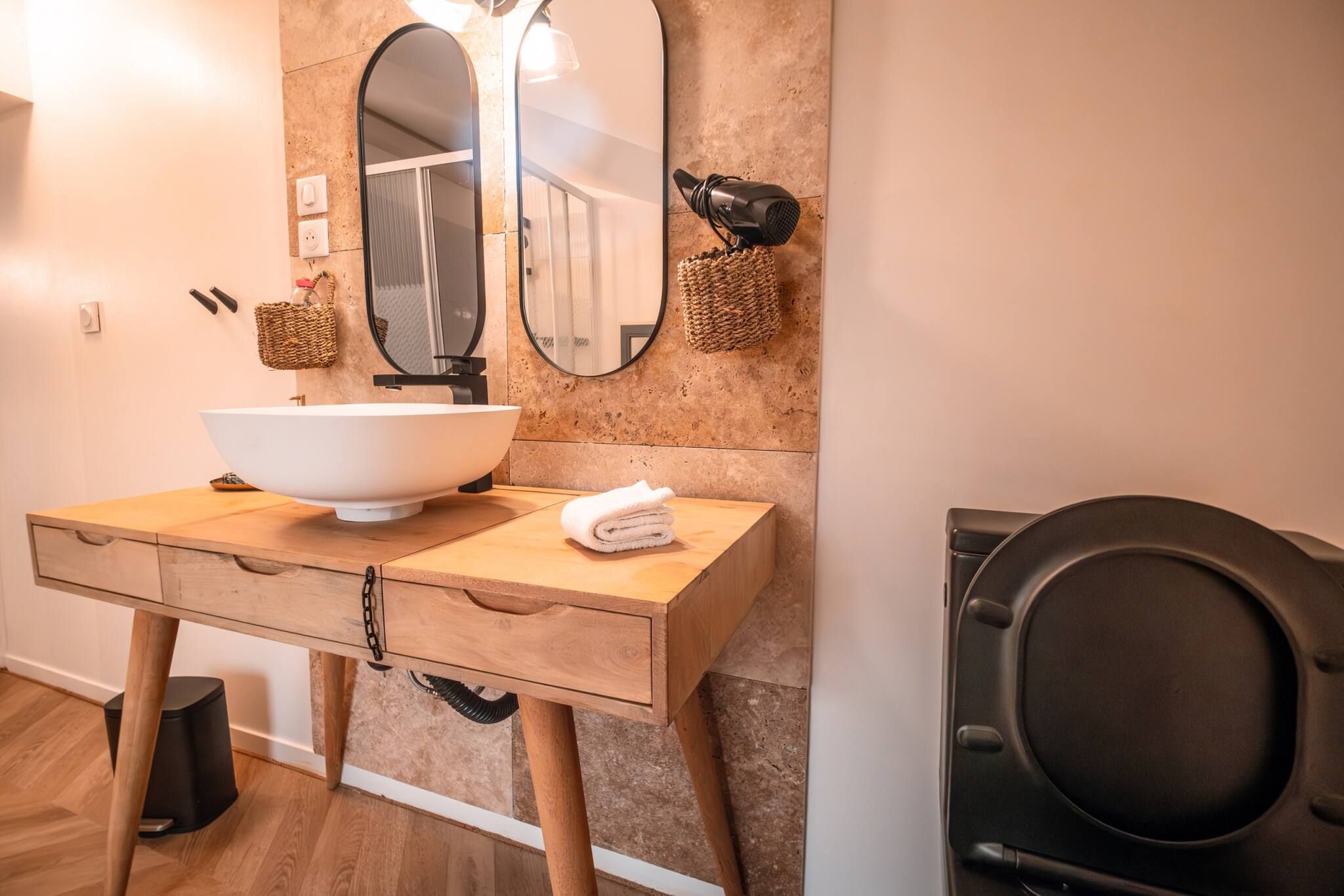 Un bagno con un mobile bagno in legno, un lavandino bianco, uno specchio grande e un asciugamano sul ripiano.