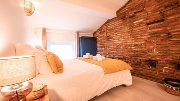 Een hotelkamer met een bed, een lamp, een houten nachtkastje en een bakstenen muur.