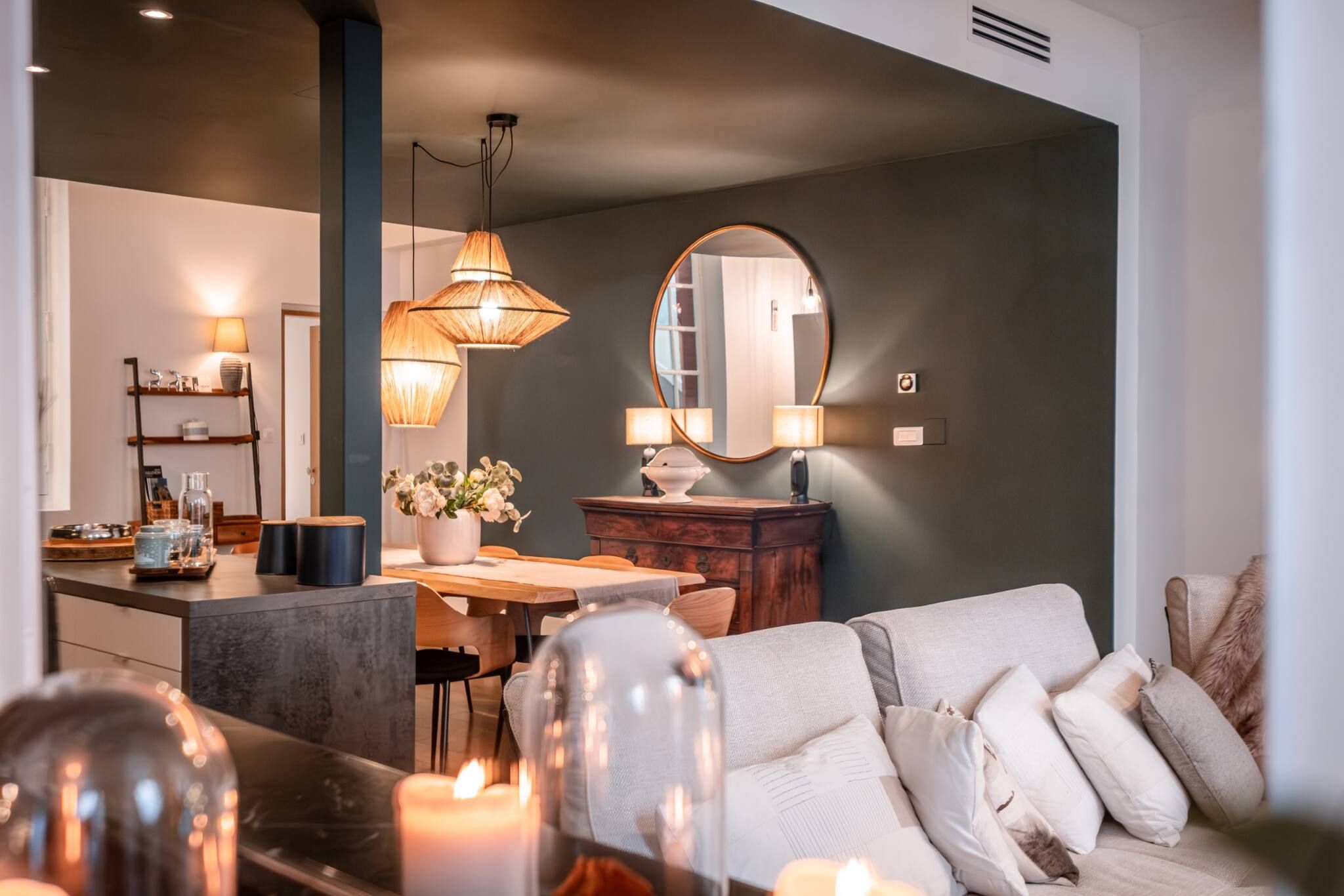A modern living room with a sofa, a dining table, and a kitchen area in the background.
