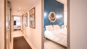 A hotel room with a bed, a blue accent wall, a wreath decoration, and a framed picture on the wall.