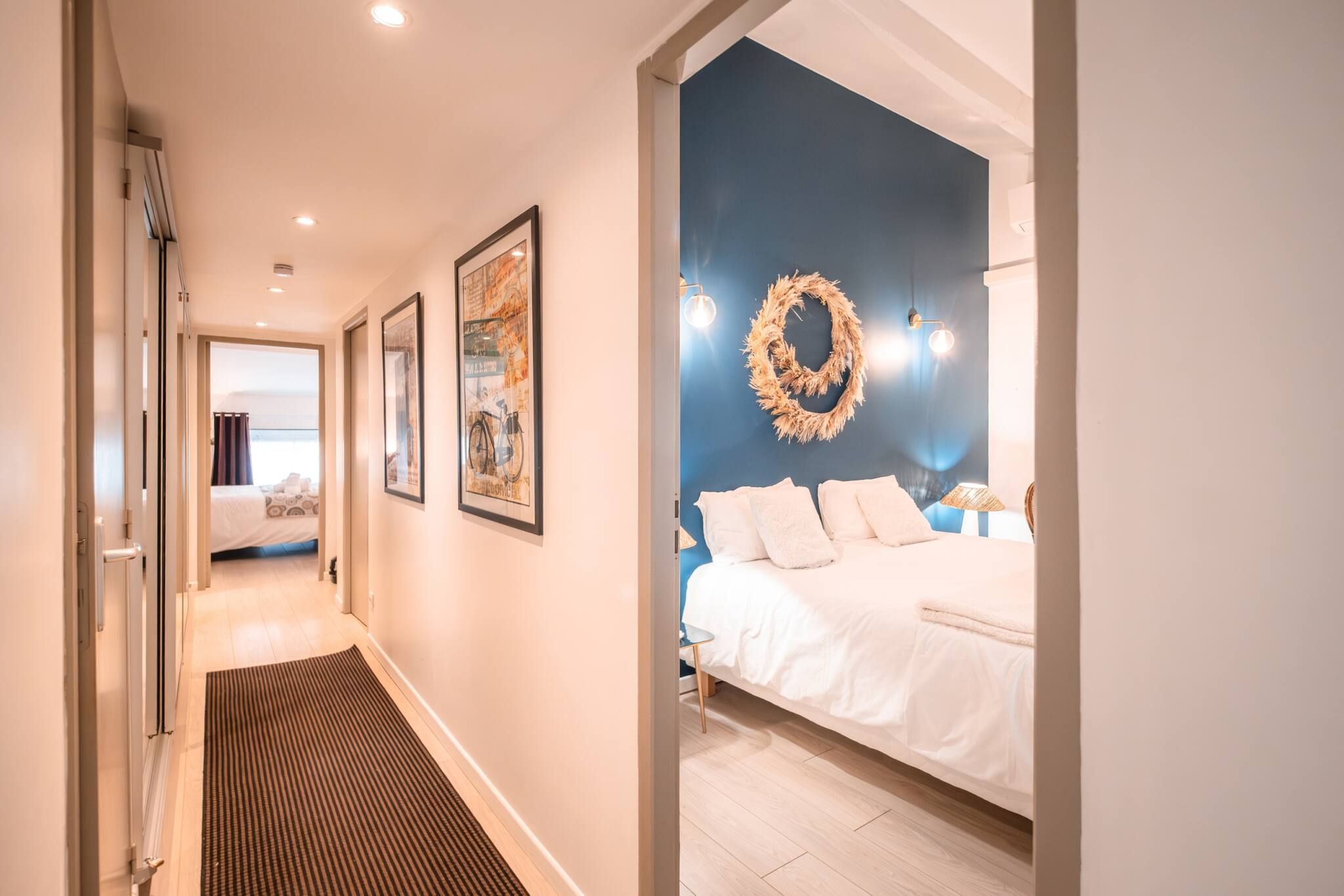 Ein Hotelzimmer mit einem Bett, einer blauen Akzentwand, einem Kranz und einem gerahmten Bild an der Wand.