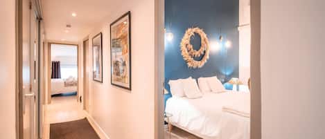 A hotel room with a bed, a blue accent wall, a wreath decoration, and a framed picture on the wall.